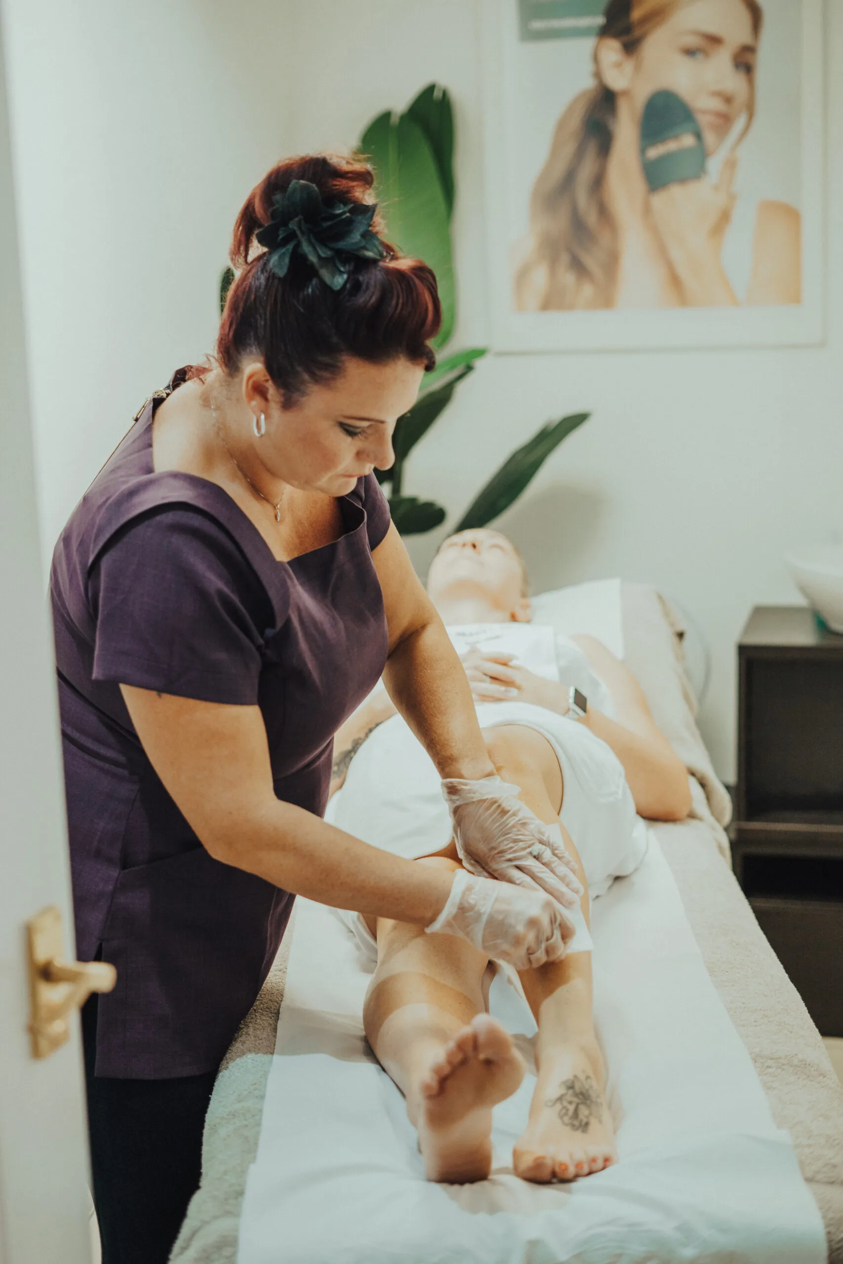 A therapist carrying out leg waxing in a Beauty Island treatment room