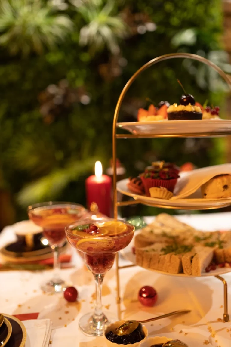 Afternoon tea stand and a drink beside a candle on a festive table
